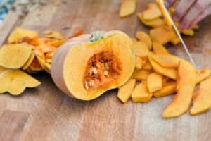 Half a Hokkaido pumpkin and pumpkin wedges, split on a wooden board with a chef's knife Half a Hokkaido pumpkin and pumpkin wedges, split on a wooden board with a chef's knife